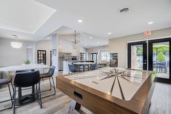 A shiny table with a wooden top and a black handle is in the center of the room.